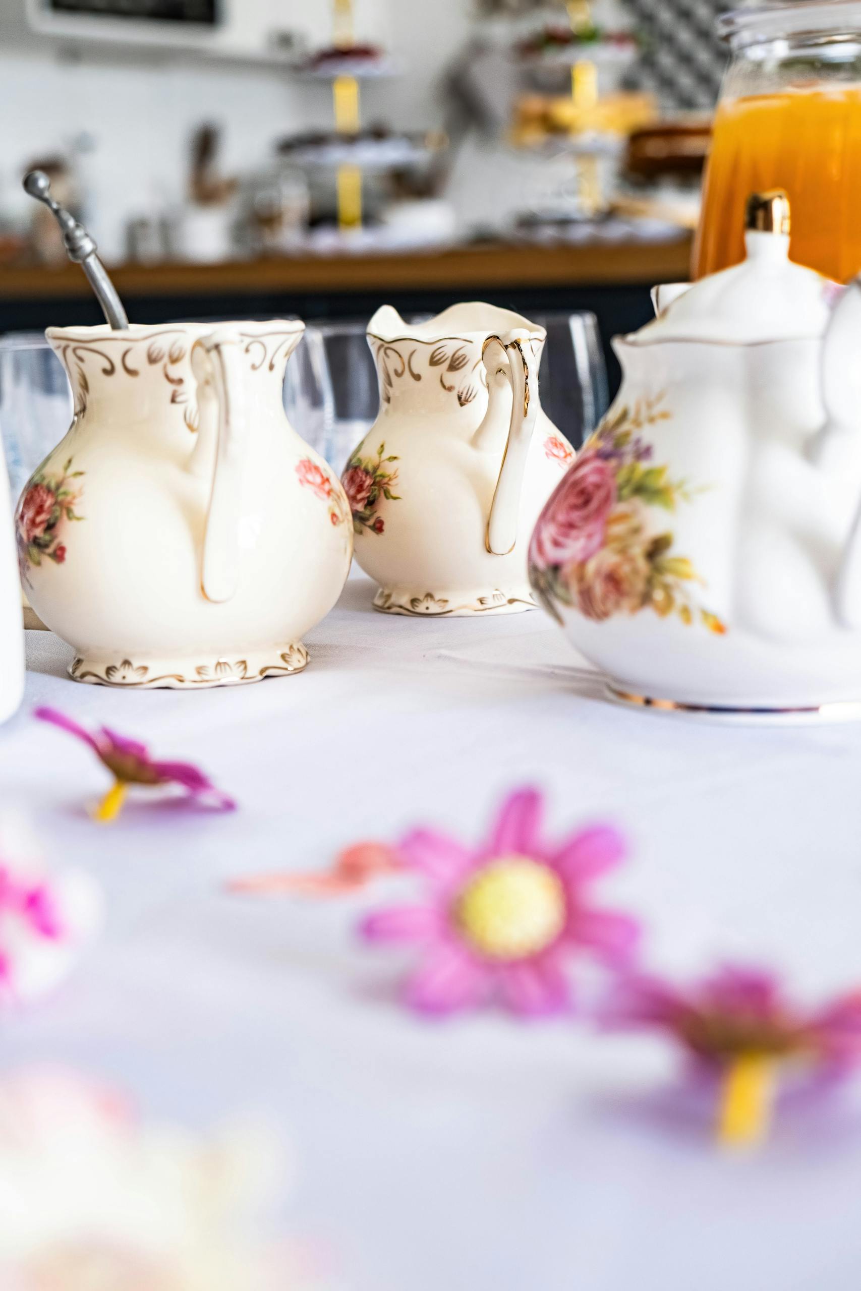 A close-up of an elegant tea set with floral decorations on a white tablecloth, perfect for tea time.