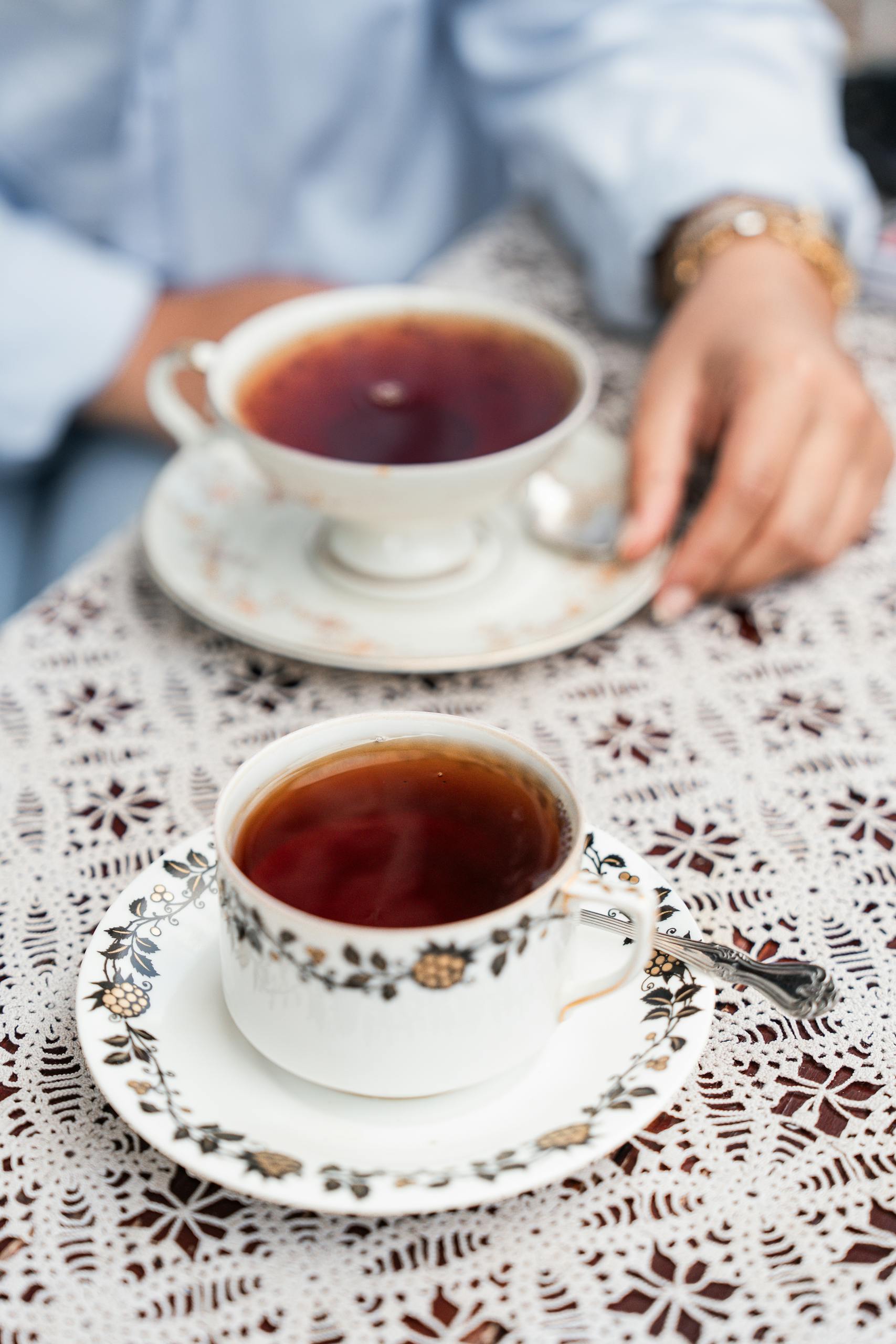 Detailed view of ornate tea cups on a lace tablecloth in Istanbul, with a relaxed atmosphere.